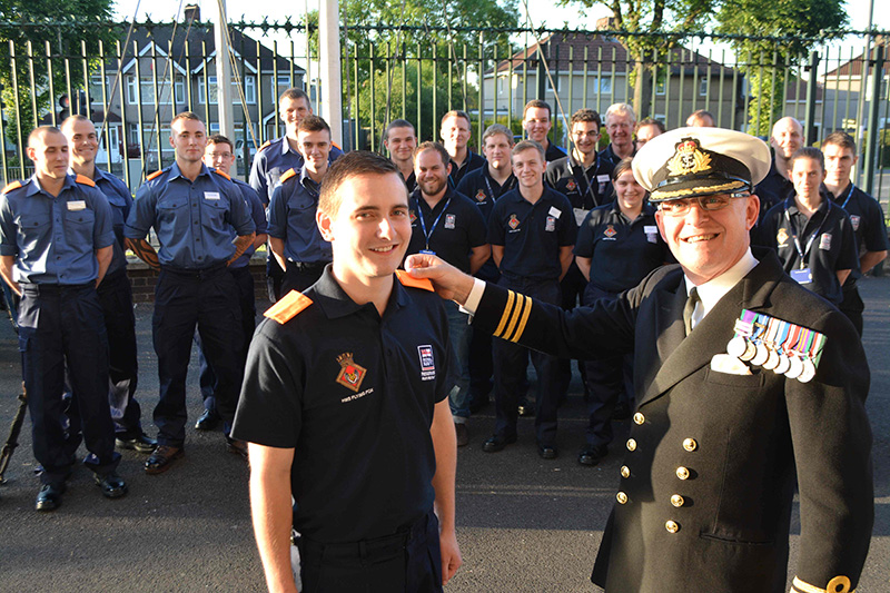 Commander Dave Bucknell, Commanding Officer of HMS FLYING FOX, pins ‘tabs’ on probationary recruit Daniel Arnell to mark his formal enlistment as a Recruit, ready to start Phase 1 training.